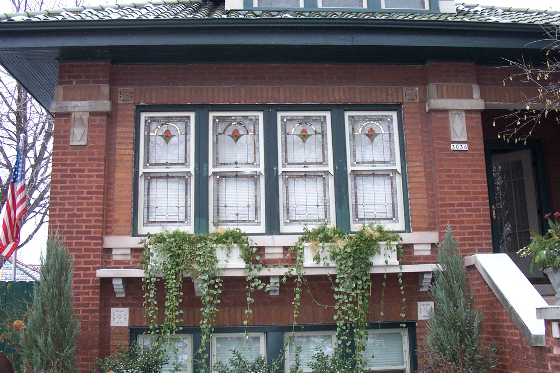 front view of a Chicago style red brick bungalow home displaying four stained glass windows with Angel Gilding mirrors 