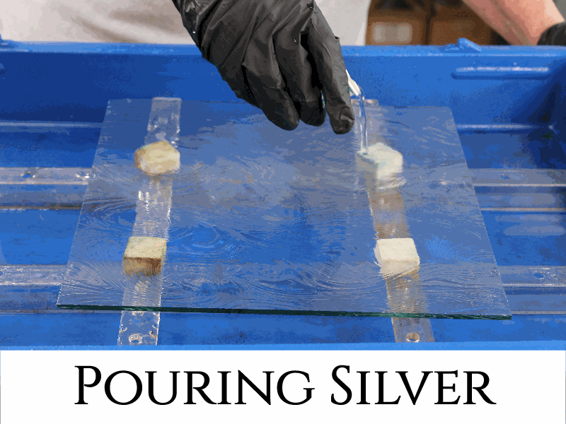a person using the Pump Spray Assembly to spray silver on the back of a oval glass tray that is supported in the blue bench kit tray