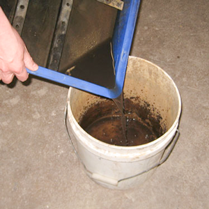 Pouring mirror waste water into a white bucket to treat it with a waste treatment kit