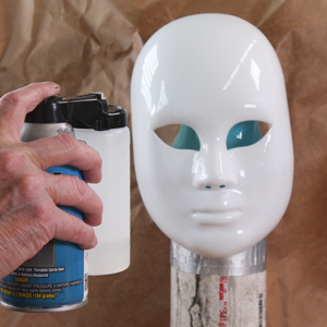 Crown Spra-tool spraying clear basecoat on a plastic face mask to prepare for silvering